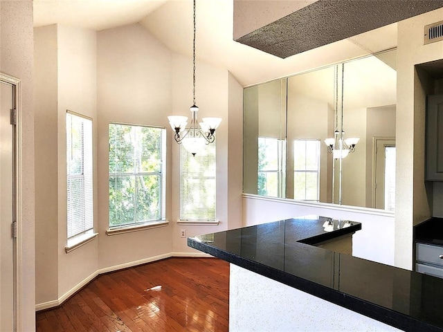 kitchen with a notable chandelier, pendant lighting, lofted ceiling, and hardwood / wood-style flooring