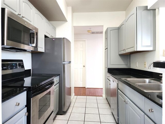 kitchen with white cabinets, appliances with stainless steel finishes, light tile patterned floors, and sink