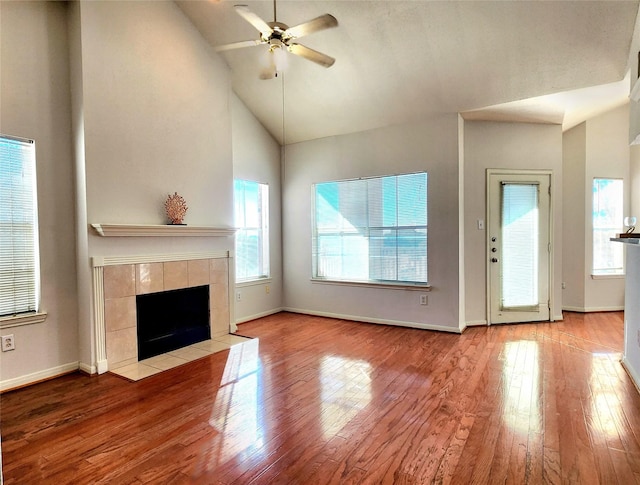 unfurnished living room featuring ceiling fan, light hardwood / wood-style floors, a fireplace, and high vaulted ceiling