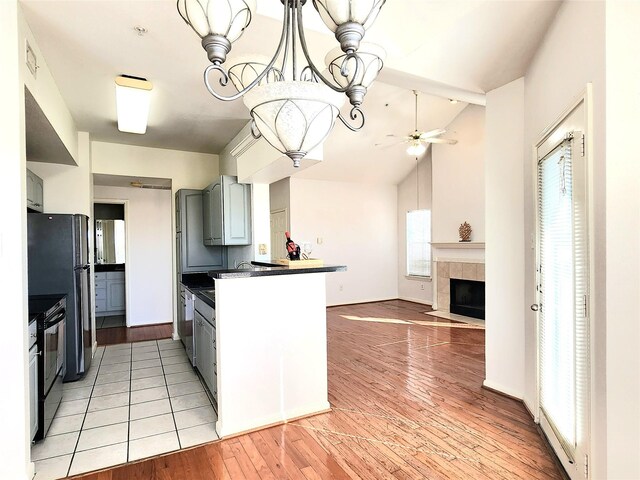 kitchen with light hardwood / wood-style floors, ceiling fan, a fireplace, gray cabinets, and black / electric stove