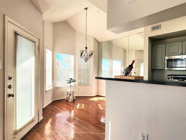 kitchen with a notable chandelier, pendant lighting, lofted ceiling, hardwood / wood-style flooring, and range