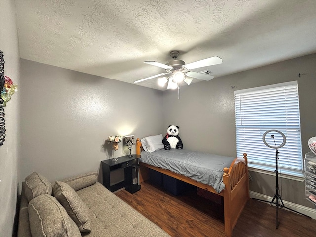 bedroom featuring ceiling fan, dark hardwood / wood-style floors, a textured ceiling, and multiple windows