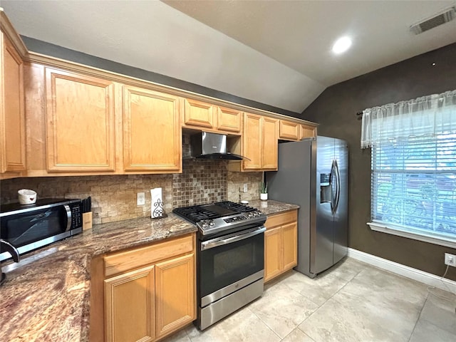 kitchen with dark stone counters, vaulted ceiling, decorative backsplash, appliances with stainless steel finishes, and extractor fan