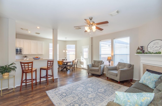 living room featuring dark hardwood / wood-style flooring, ceiling fan, and a fireplace