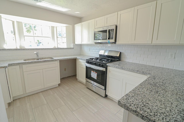 kitchen with light stone countertops, stainless steel appliances, and sink