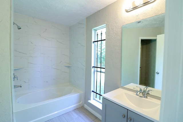 bathroom with vanity, tiled shower / bath combo, and a textured ceiling