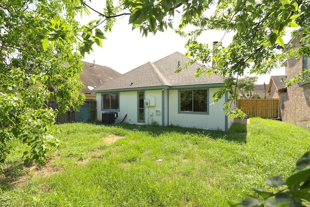 back of property featuring cooling unit and a yard