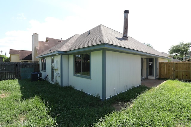 rear view of house featuring a lawn and central AC