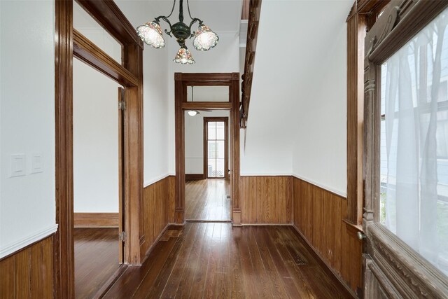 hall featuring dark wood-type flooring and a notable chandelier