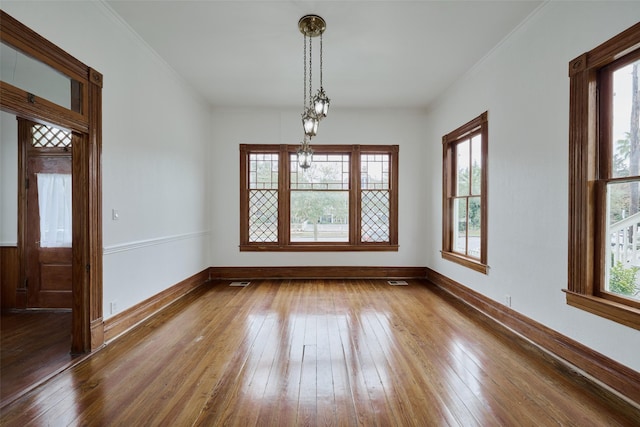 empty room with plenty of natural light, hardwood / wood-style flooring, and crown molding