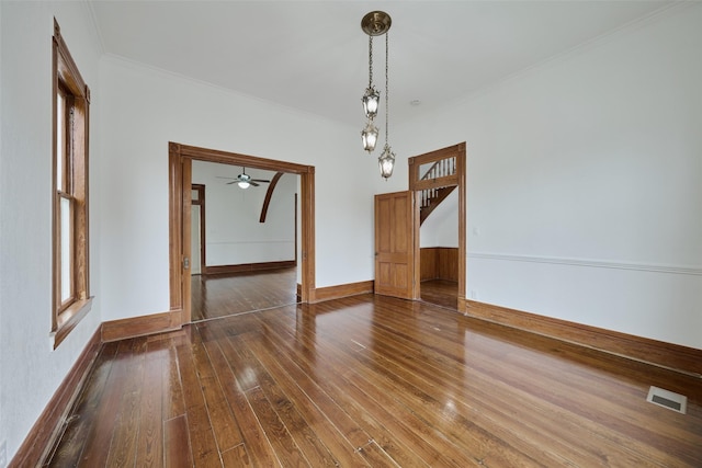 unfurnished dining area with dark wood-type flooring, ornamental molding, and ceiling fan with notable chandelier