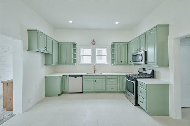 kitchen featuring green cabinets, open shelves, appliances with stainless steel finishes, and a sink