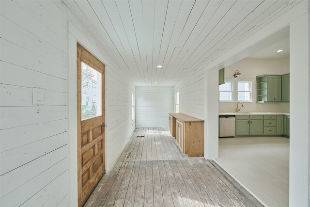 hallway with wooden ceiling, sink, wooden walls, and light hardwood / wood-style flooring