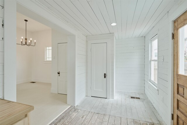 entrance foyer with an inviting chandelier, plenty of natural light, and wooden walls