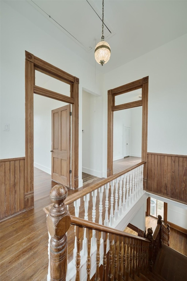 hall featuring a wainscoted wall, wood walls, and wood finished floors