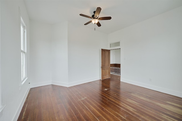 empty room with baseboards, dark wood finished floors, and a ceiling fan