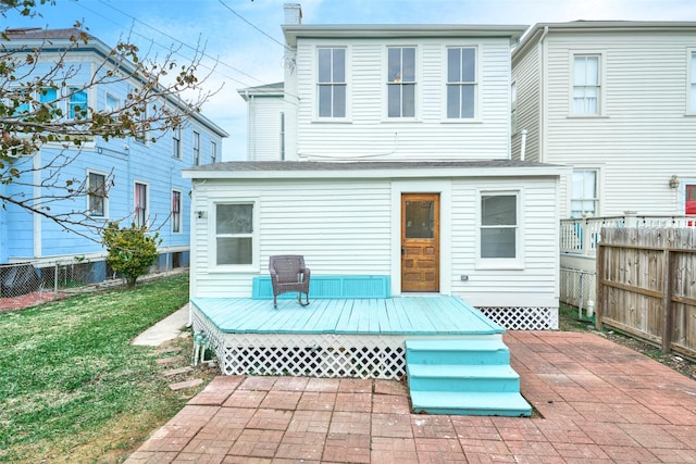 rear view of property featuring a lawn, a deck, and a patio area