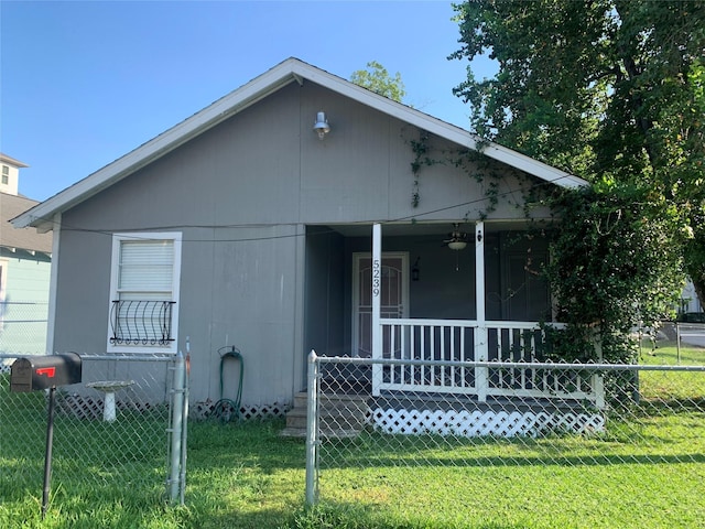 bungalow-style home with covered porch, a front yard, and fence