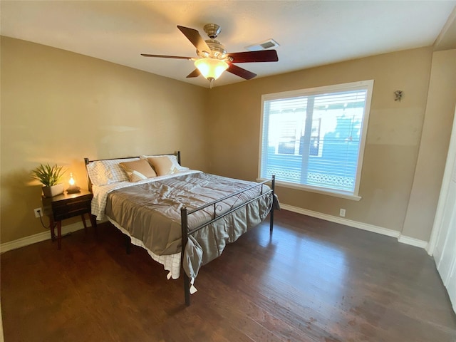 bedroom featuring ceiling fan, visible vents, baseboards, and wood finished floors