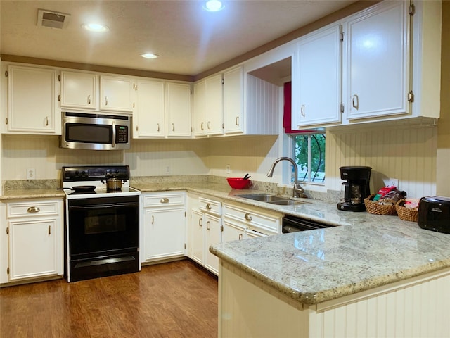 kitchen featuring visible vents, dark wood-type flooring, range with electric cooktop, a sink, and stainless steel microwave