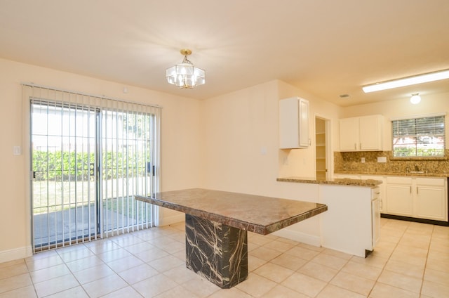 kitchen featuring light tile patterned floors, a kitchen island, a kitchen breakfast bar, decorative backsplash, and white cabinets