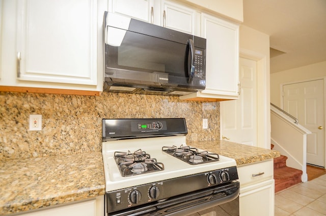 kitchen featuring light stone countertops, tasteful backsplash, white cabinetry, and gas range gas stove