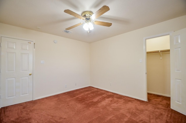 unfurnished bedroom with carpet floors, a closet, a spacious closet, and ceiling fan