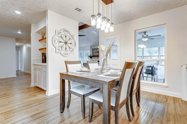 dining space with ceiling fan, light wood-type flooring, and a textured ceiling