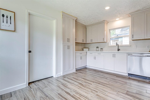 kitchen with light hardwood / wood-style flooring, stainless steel dishwasher, a textured ceiling, and sink