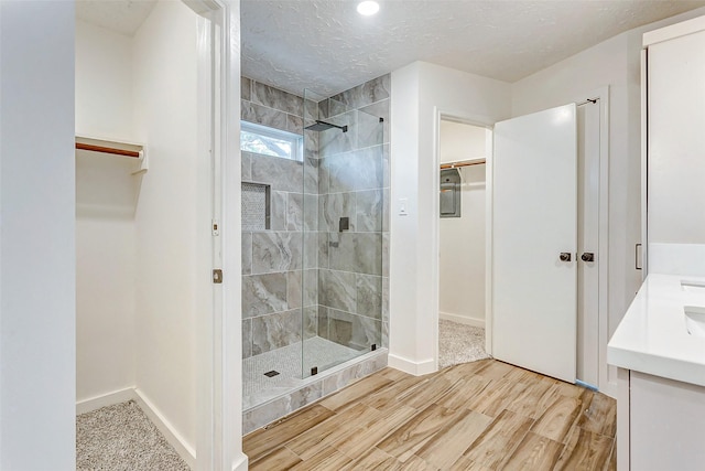 bathroom featuring a tile shower, vanity, and a textured ceiling