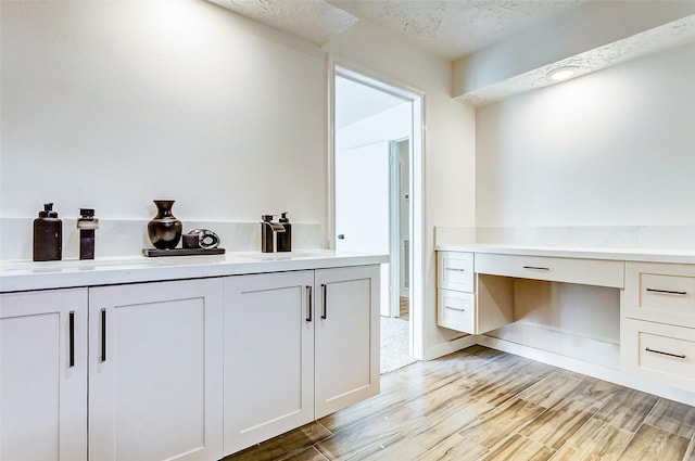 bathroom with hardwood / wood-style floors, vanity, and a textured ceiling