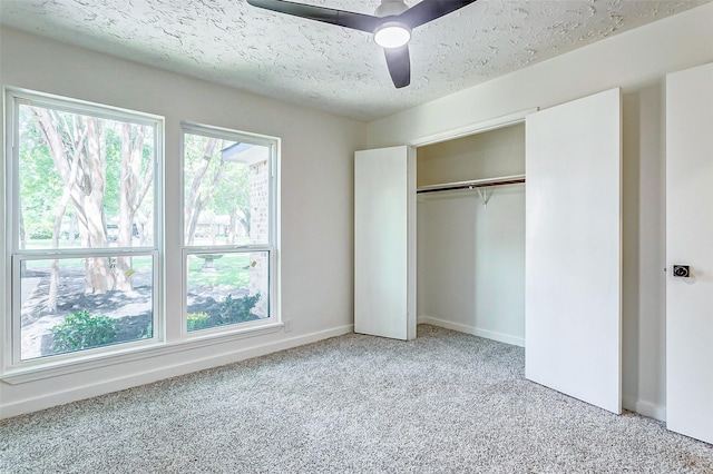 unfurnished bedroom with carpet flooring, ceiling fan, a closet, and a textured ceiling