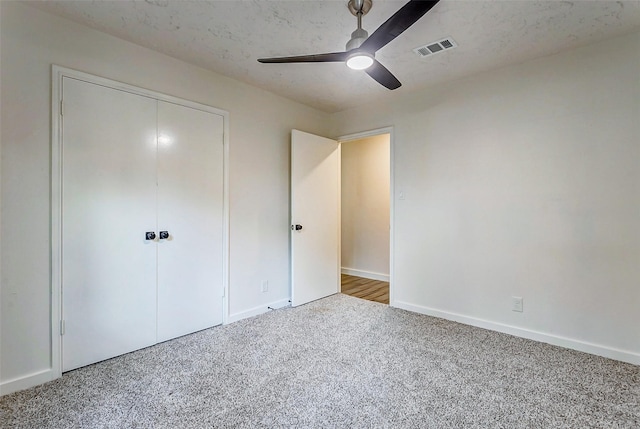 unfurnished bedroom with carpet flooring, a textured ceiling, a closet, and ceiling fan