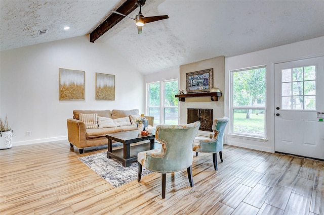 living room featuring vaulted ceiling with beams, a large fireplace, plenty of natural light, and ceiling fan