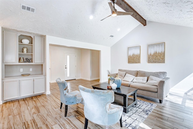 living room featuring light wood-type flooring, a textured ceiling, lofted ceiling with beams, and ceiling fan