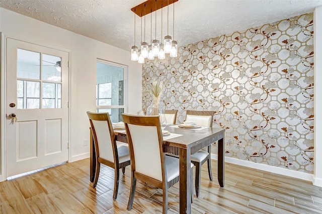 dining space with light wood-type flooring and a textured ceiling