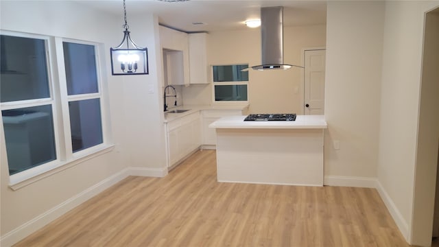 kitchen with pendant lighting, white cabinets, sink, island range hood, and gas cooktop