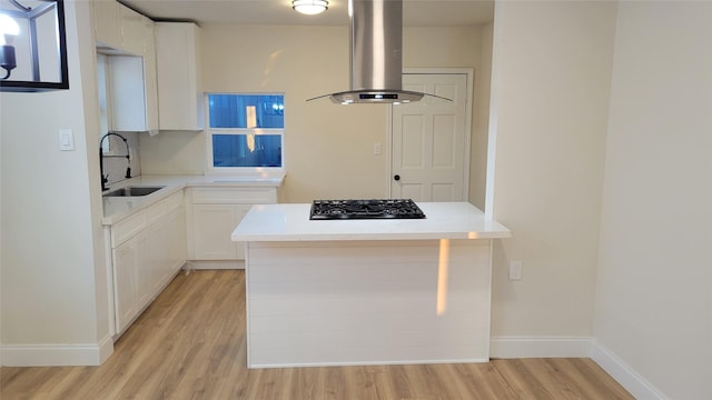 kitchen with white cabinetry, sink, island exhaust hood, black gas stovetop, and light wood-type flooring