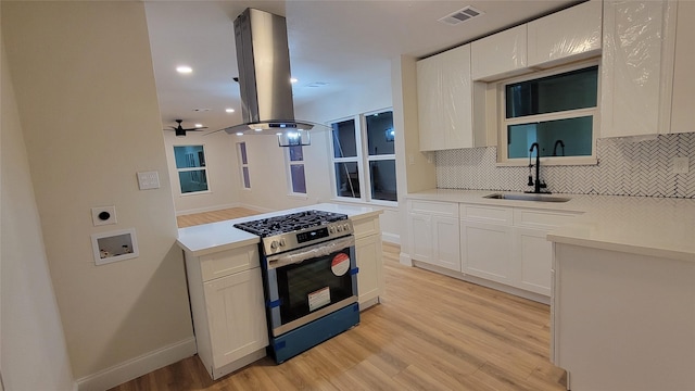 kitchen with white cabinets, stainless steel gas range oven, sink, and island exhaust hood