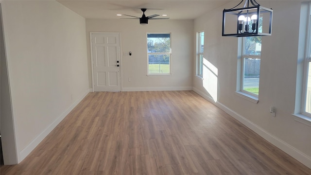 interior space featuring ceiling fan with notable chandelier and hardwood / wood-style flooring