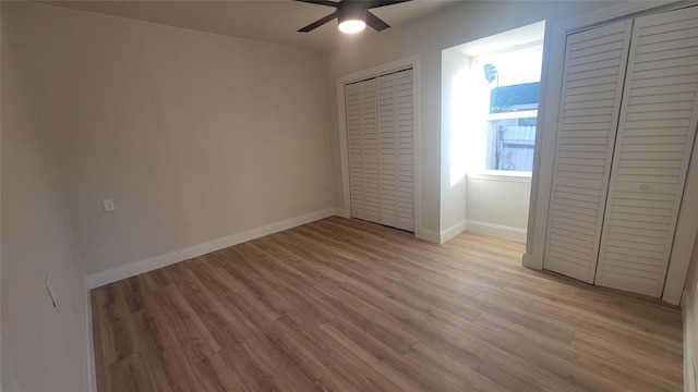 unfurnished bedroom with ceiling fan, light hardwood / wood-style floors, and two closets