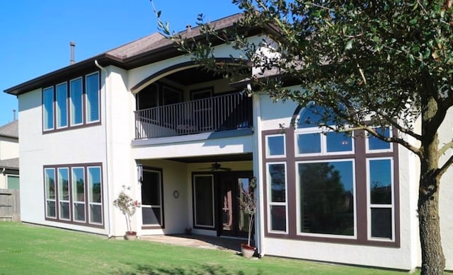 rear view of house featuring a balcony and a lawn