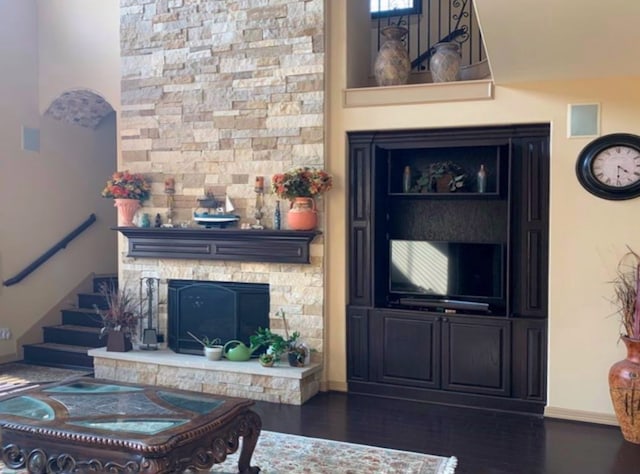 living room with a stone fireplace and dark hardwood / wood-style flooring