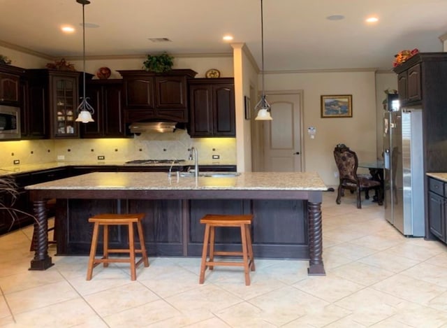 kitchen with a kitchen bar, a center island with sink, ornamental molding, and sink