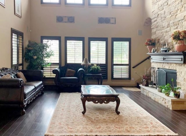 living room with dark hardwood / wood-style flooring, a fireplace, and a high ceiling