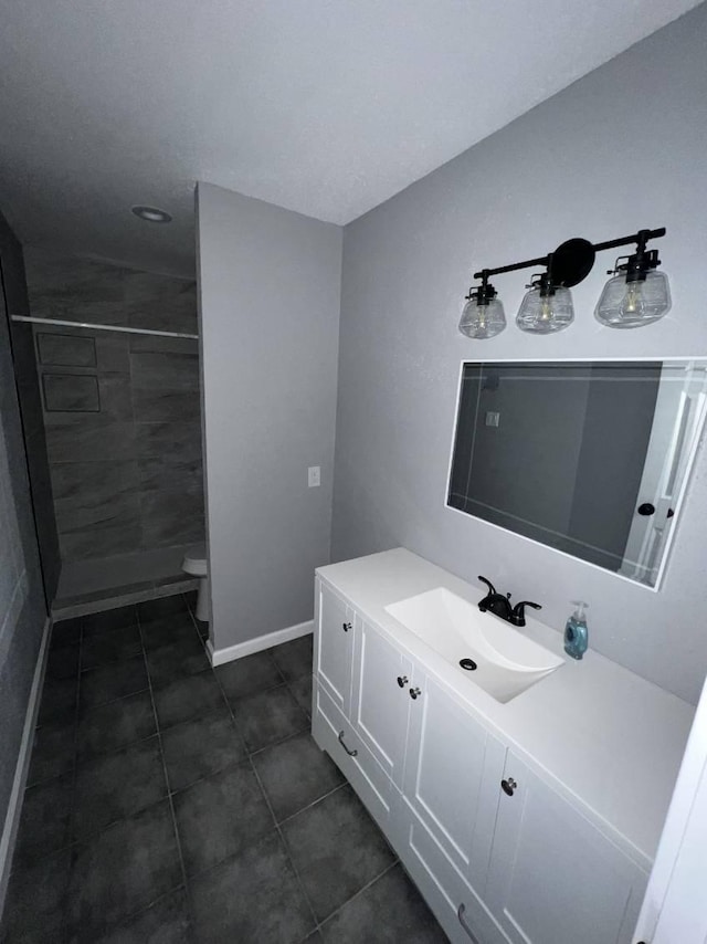 bathroom featuring a tile shower, vanity, and toilet