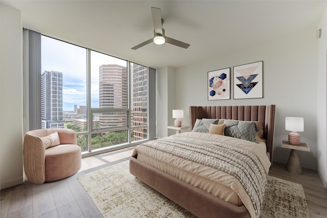 bedroom featuring multiple windows, ceiling fan, expansive windows, and light hardwood / wood-style floors