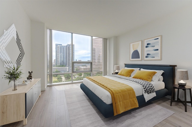 bedroom featuring light wood-type flooring and a wall of windows