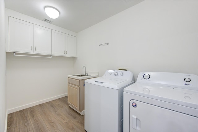 clothes washing area featuring cabinets, separate washer and dryer, light hardwood / wood-style floors, and sink