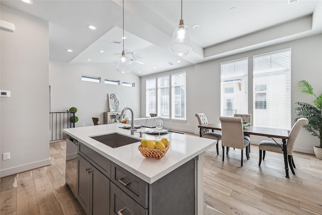 kitchen featuring ceiling fan, sink, dishwasher, light hardwood / wood-style flooring, and a center island with sink